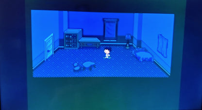Video game screen showing a character in a room with blue walls and furniture.
